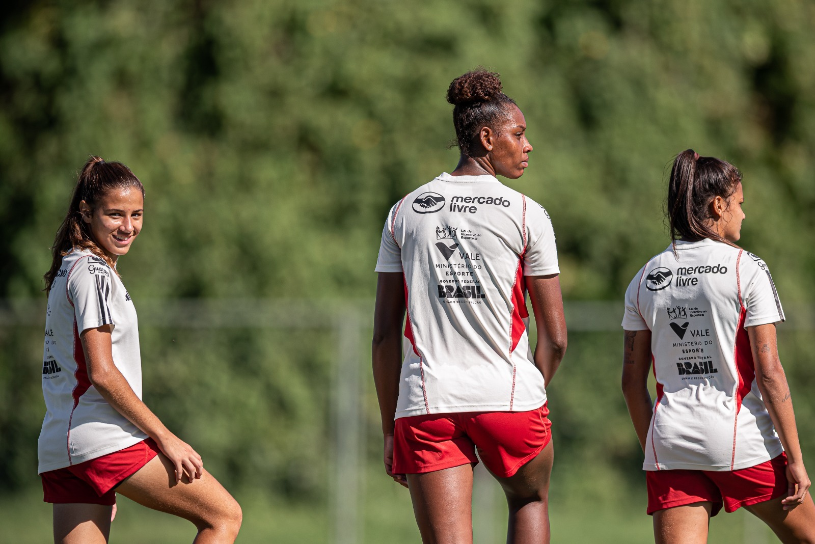 Três jogadoras de futebol vestem a camisa do flamengo com o símbolo da Vale
