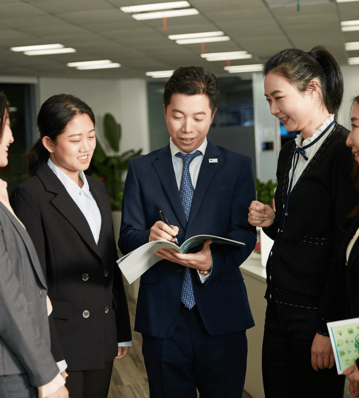 group of Chinese executives gathered. They are all wearing social black clothes. There are three women and one man holding papers