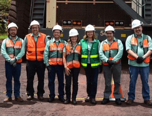 Um grupo de empregados Vale, todos de capacete e coletes de proteção, pousam para foto em uma área externa